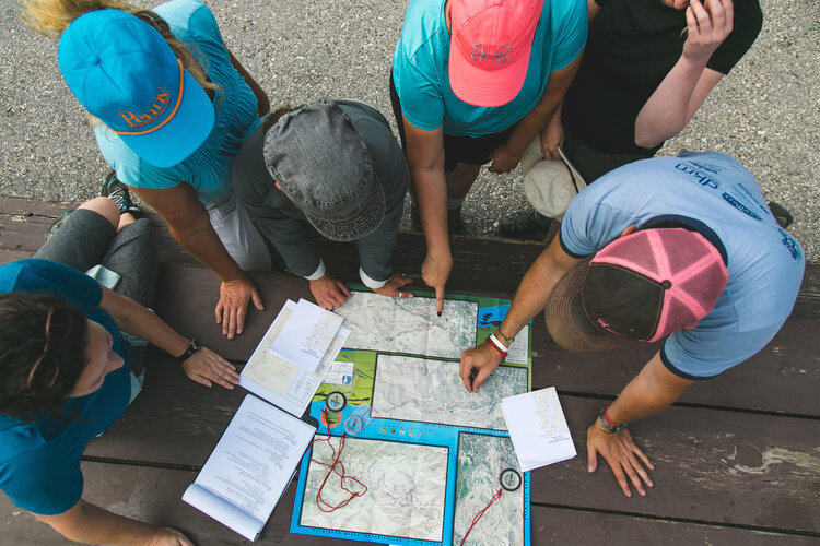a group of people gathered around a map on a picnic table